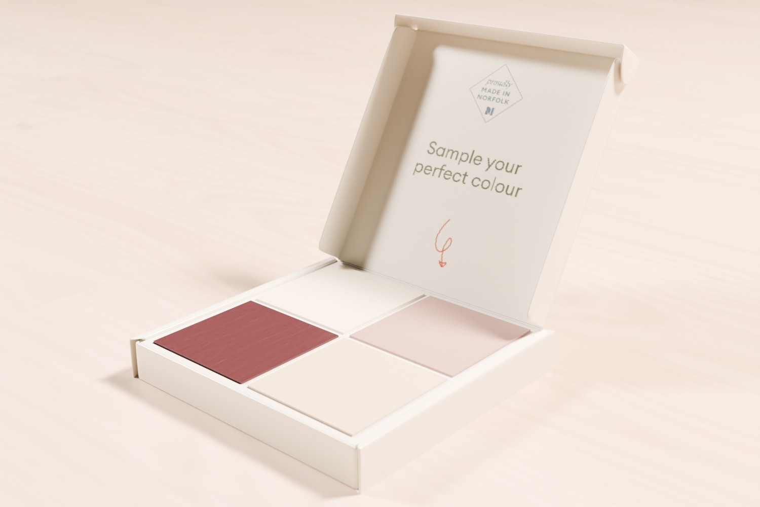 Open makeup palette with four square shades in burgundy, pink, and two light beige tones on a light surface. The inside lid reads \"Sample your perfect colour\"